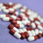 Pills are scattered on a purple surface.