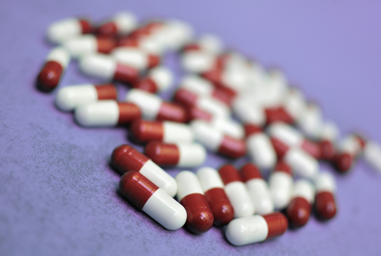 Pills are scattered on a purple surface.