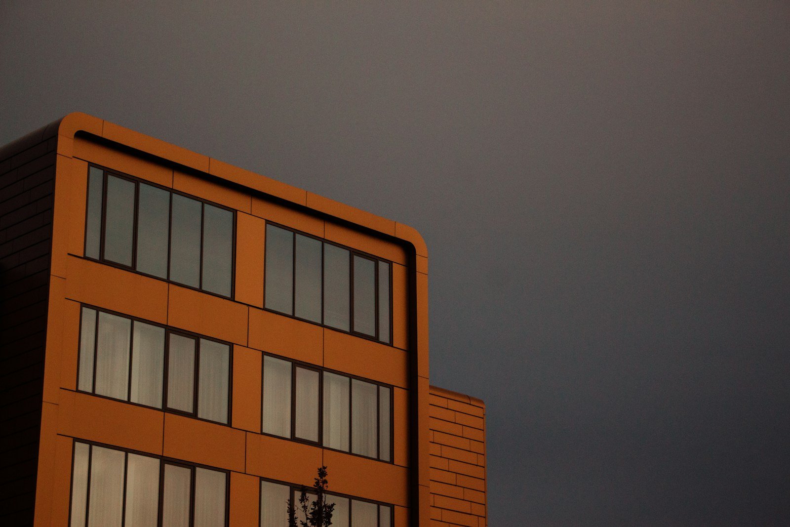a tall orange building sitting under a cloudy sky